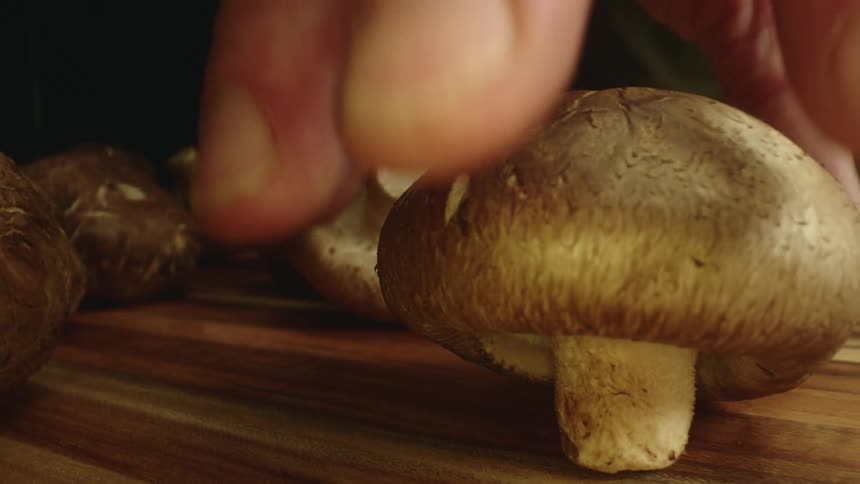 A man is cooking with mushrooms indoors