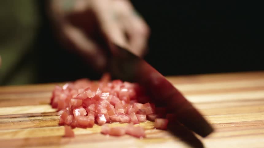 A chef diced tomatoes and wipes off his knife