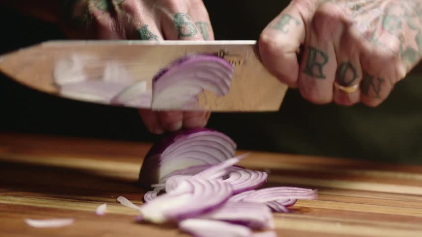 A person cutting up red onion