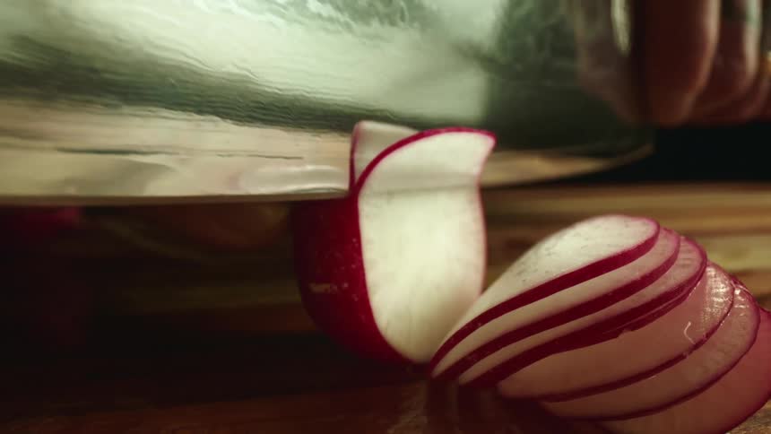 A person cutting a vegetable with a knife on a cutting board