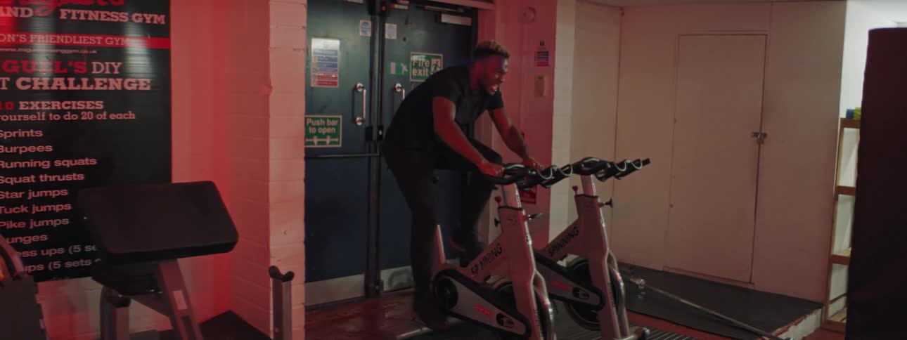 A man is using the exercise bike in the gym