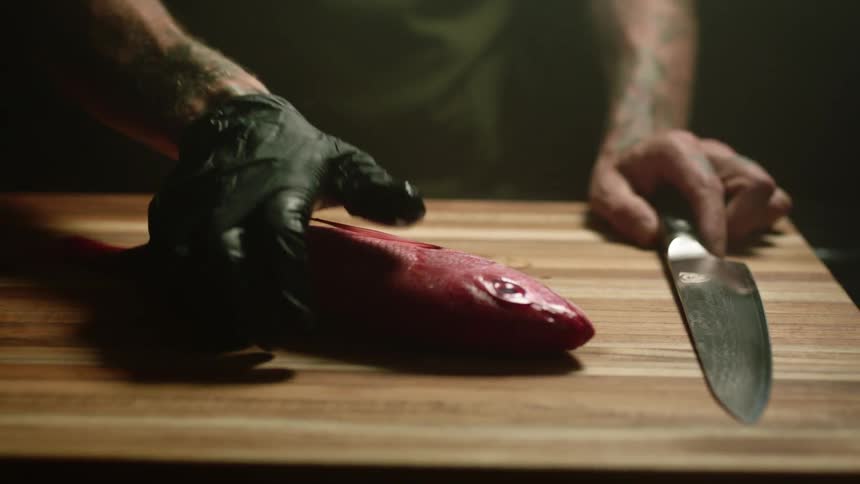 A person is cutting a fish with a knife