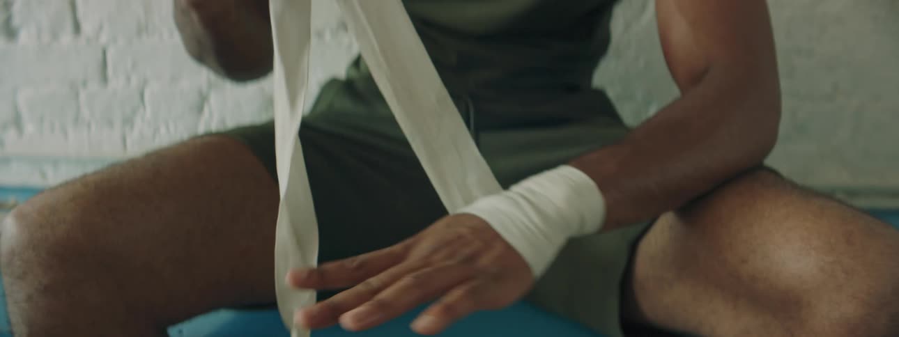 A male athlete is putting tape on his hands to work out