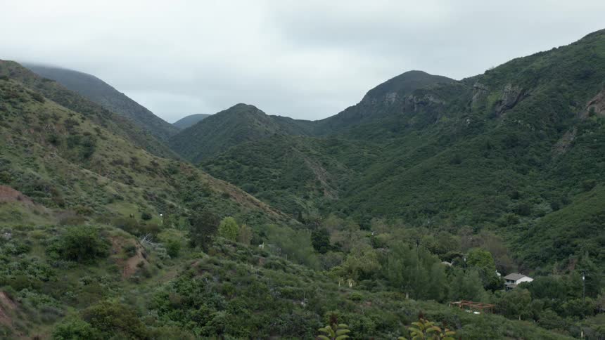A house sits nestled in the valley of hills