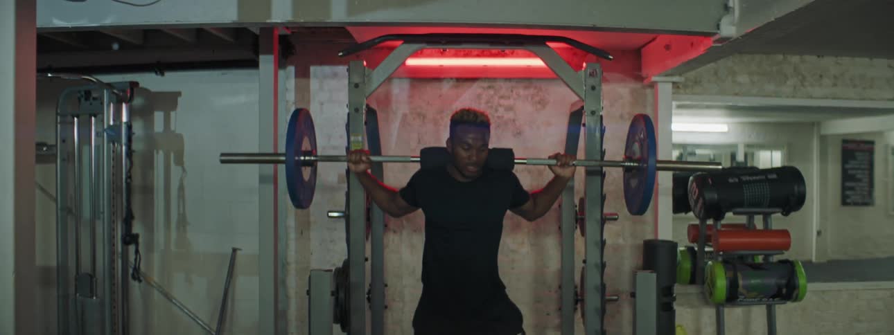 A man walks up to weights in a gym and does a shoulder workout