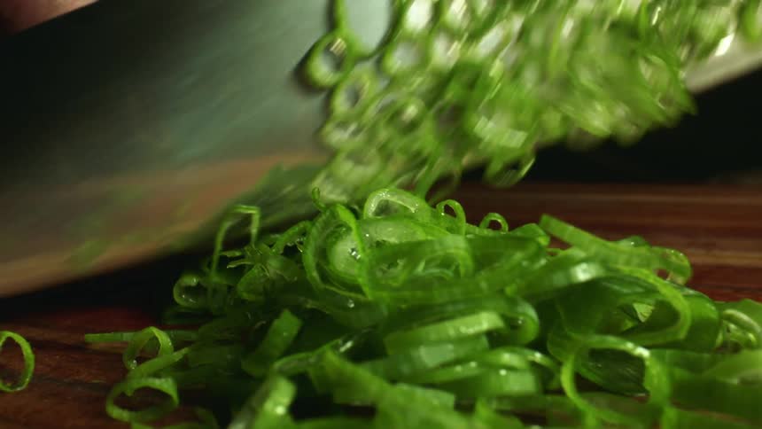 A man is cutting chives with a kitchen knife
