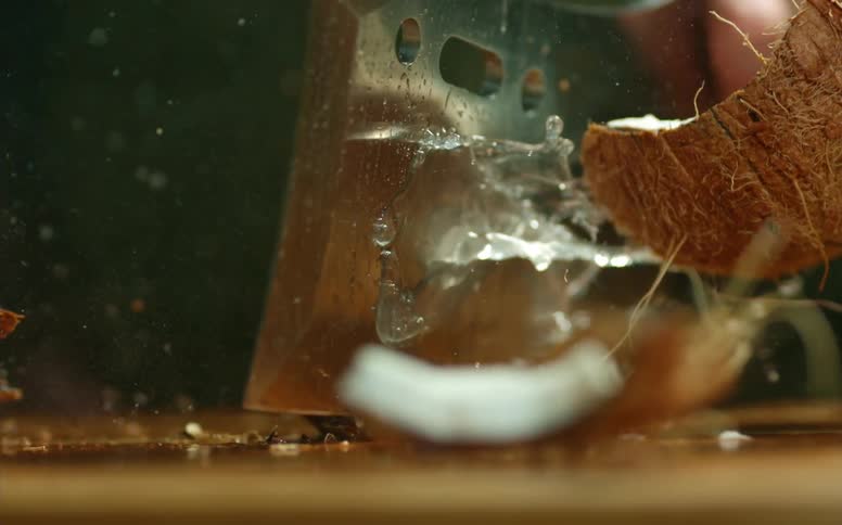 A man chops a coconut and juice sprays out