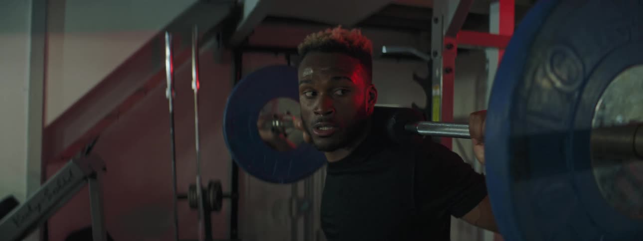 A man does squats with weights and then replaces the bar on a rack