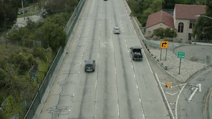 Cars driving down a road near houses