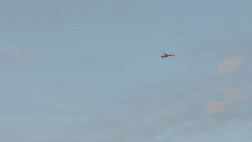 A helicopter flying over some poles