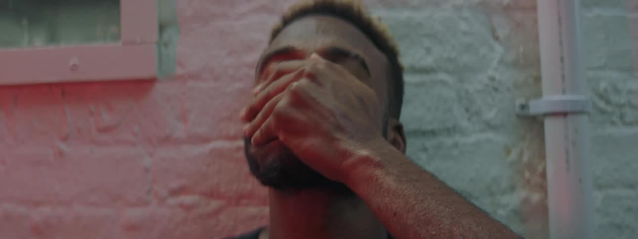 A man leans his head against a brick wall