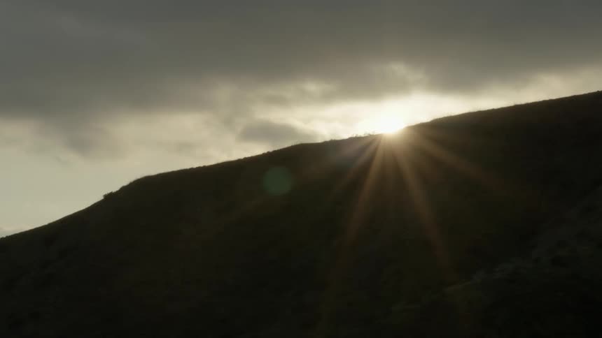 Sunlight shining over a silhouetted slope in nature