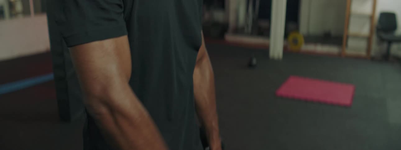 Young strong muscular man lifting dumbbells inside a gym