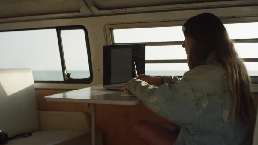 A woman sitting in a van with a laptop