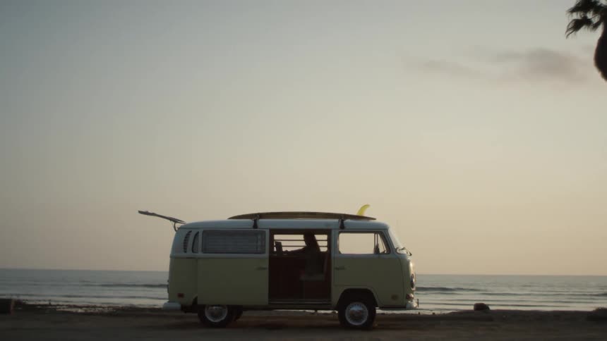A person sits in a van parked on the beach