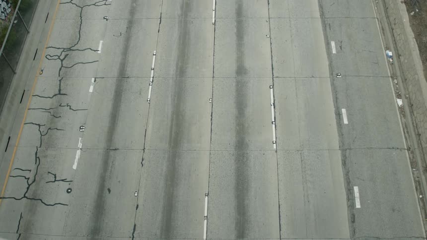 A highway with vehicles next to a fence and a wall with graffiti