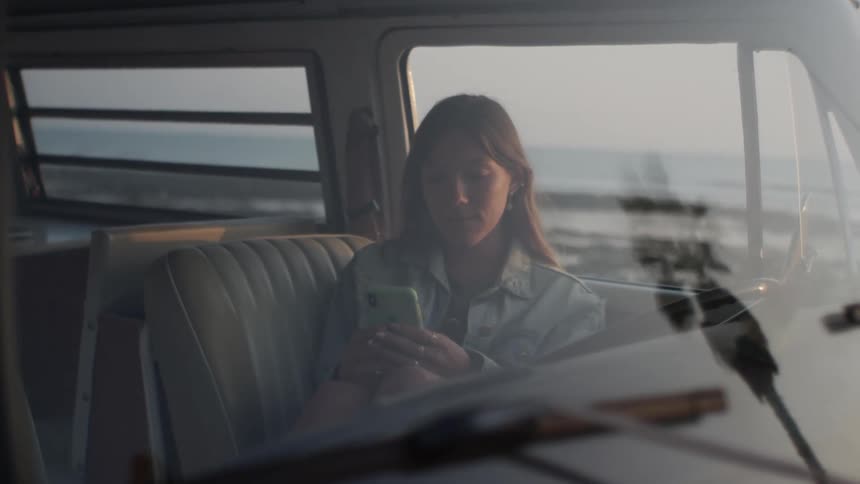 A woman sitting in a vehicle with a phone