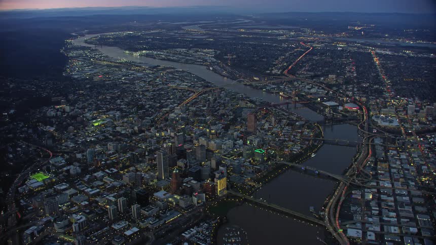 The city of Portland, Oregon with a river and bridges buildings and skyscrapers in this wide tilt up high altitude aerial shot