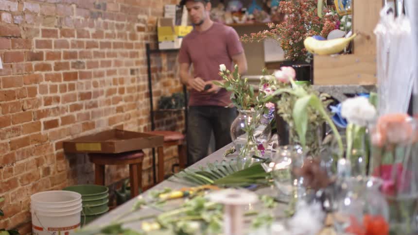 A man in a pink shirt walks past a lady holding flowers