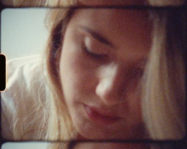 A woman in a room with a white shirt and lipstick looking down