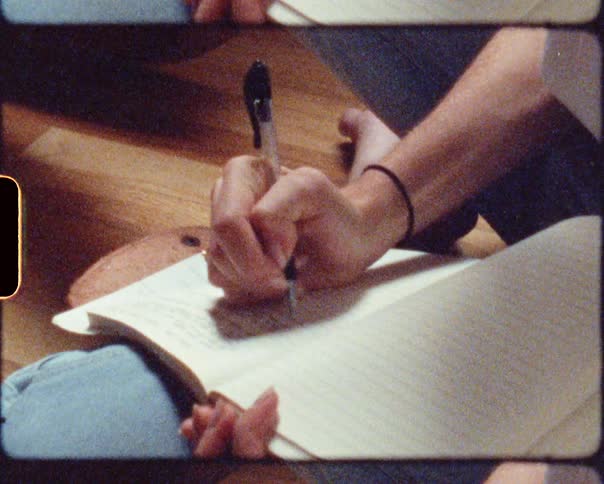 A person writing with a pen in a notebook