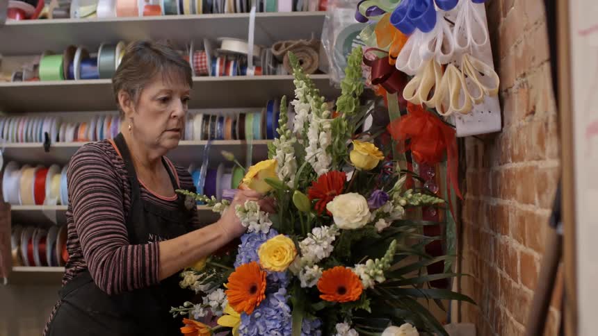A woman is arranging flowers in a shop