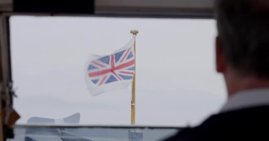 A person staring out a window at a flag