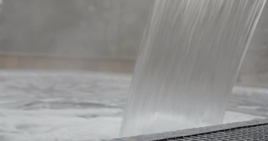 Water falling into a pool with trees in the background