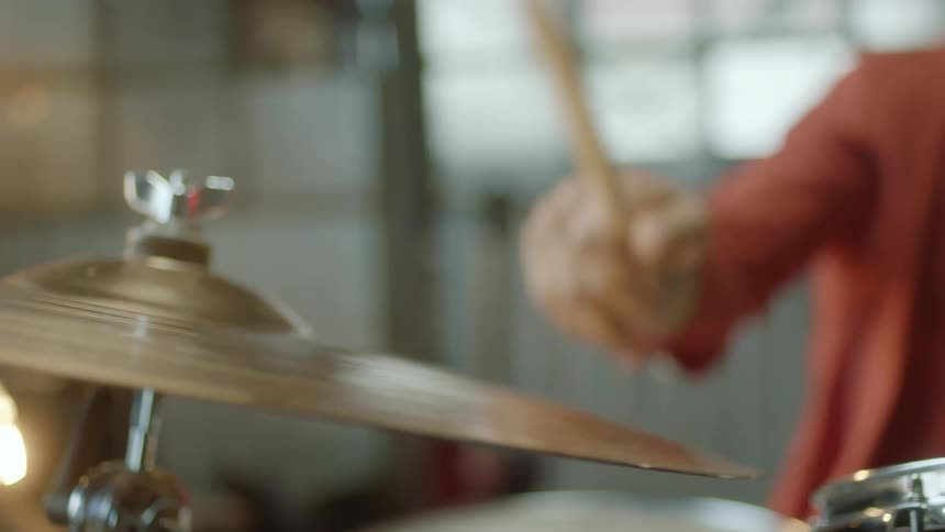 A drummer hitting a cymbal with a drumstick
