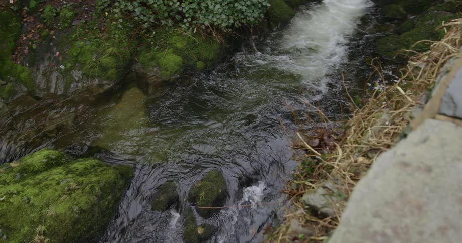 A small waterfall flowing under a stone bridge