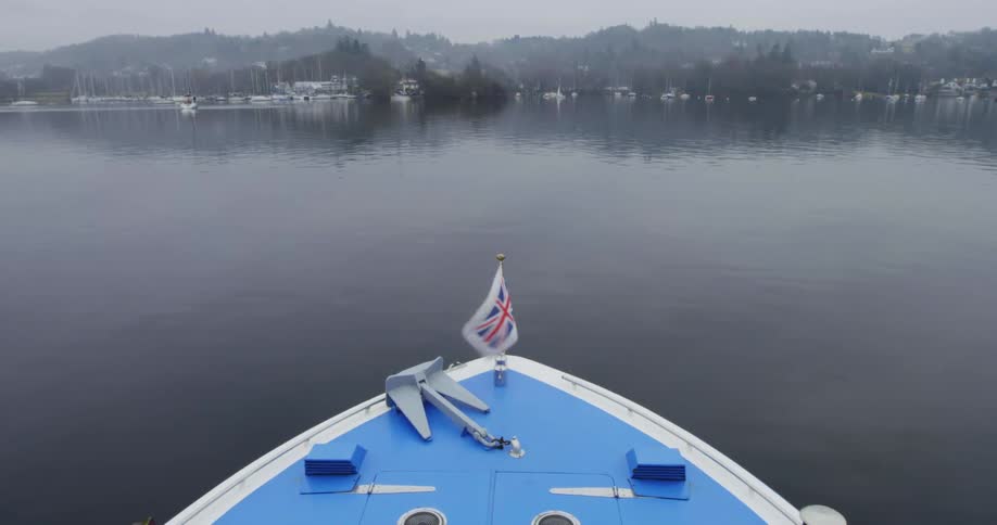 A blue boat floating on a lake on a hazy day