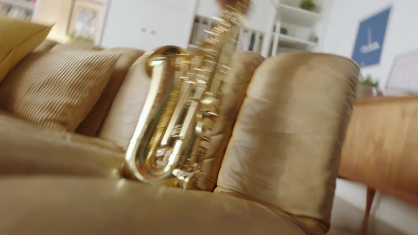 A person grabbing a saxophone off a couch