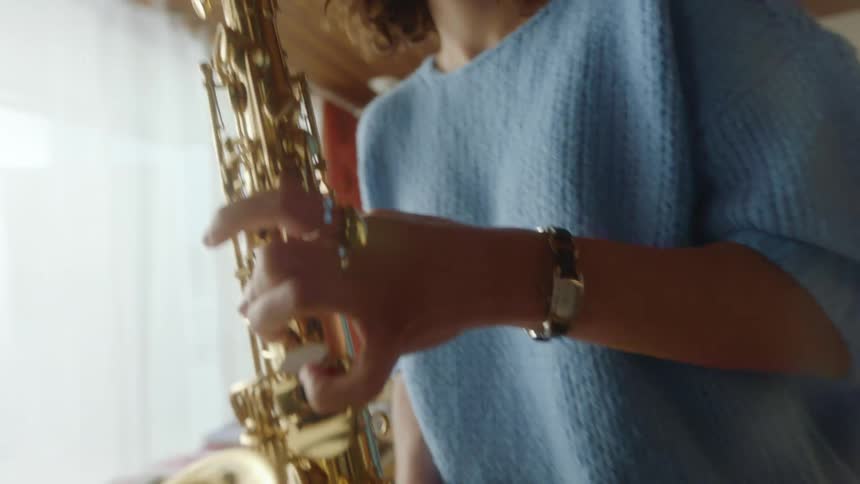 A woman dancing and playing a saxophone while standing in a living room