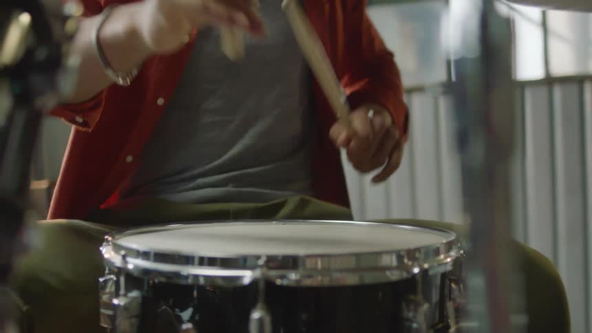 A man is playing the drums while sitting down