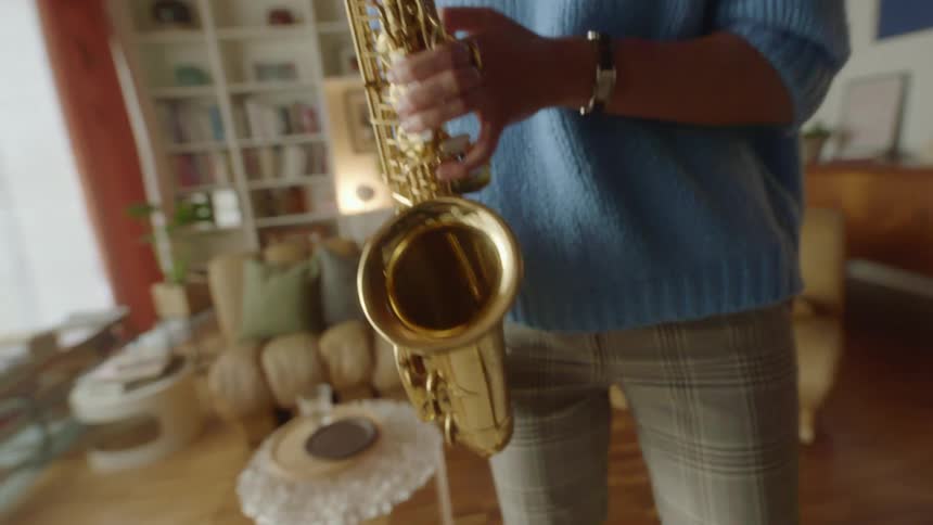 A musician plays the saxophone while swaying from side to side in the living room of a house during the day