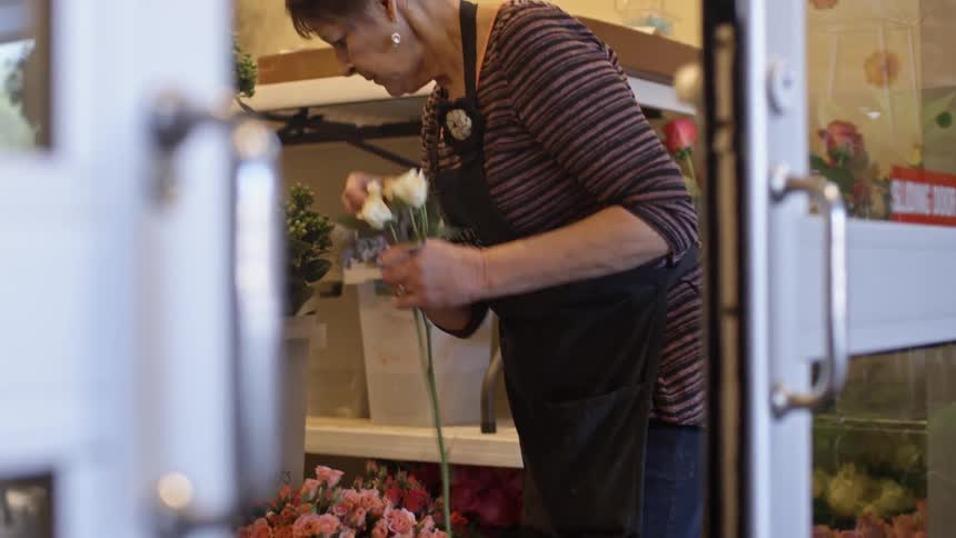 A woman picks white flowers from a pot