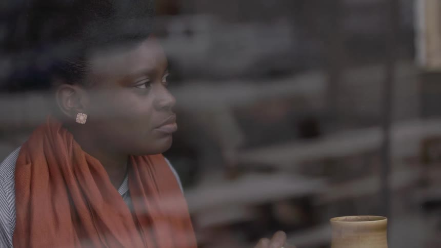Woman looks out the window of a coffee shop