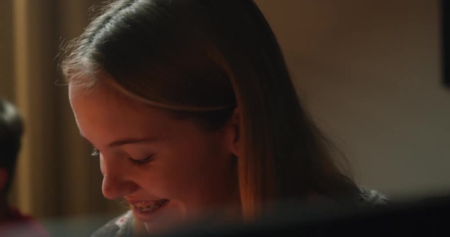 A girl in a room smiling with braces with a wall in the background