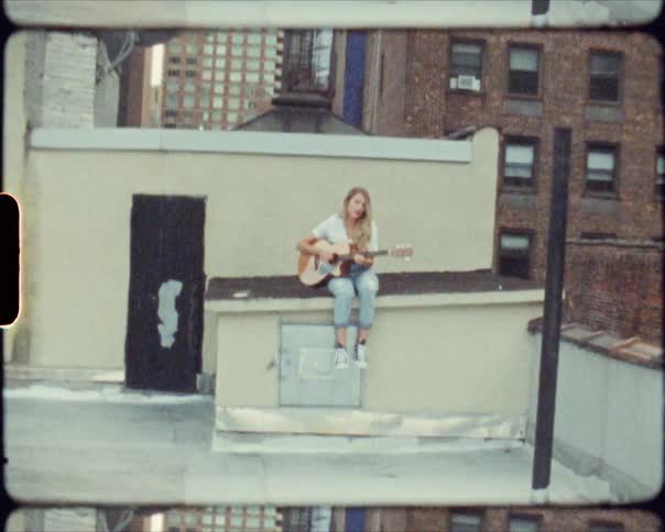 A woman is sitting with a guitar in an urban city