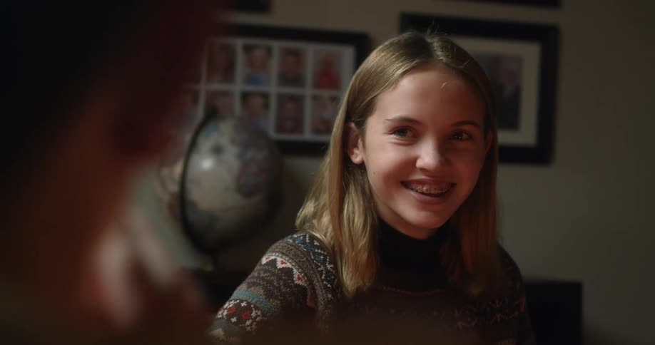A blonde girl smiling and laughing while sitting indoors