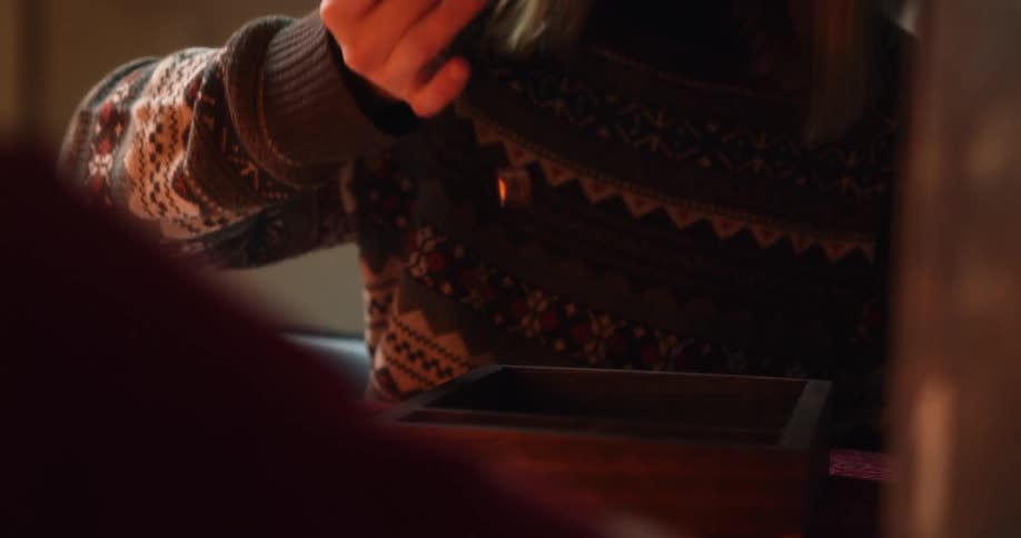 A female sitting at a table shakes and then rolls a handful of dice while playing a game