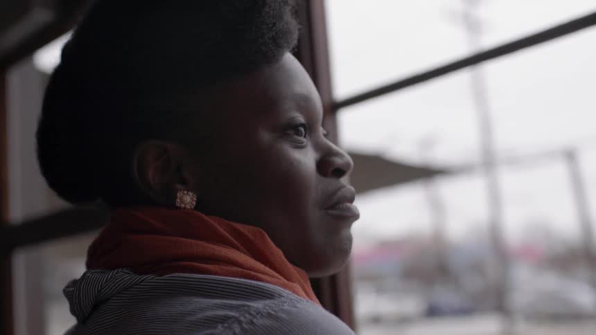 A woman smiles as she looks out the window and talks