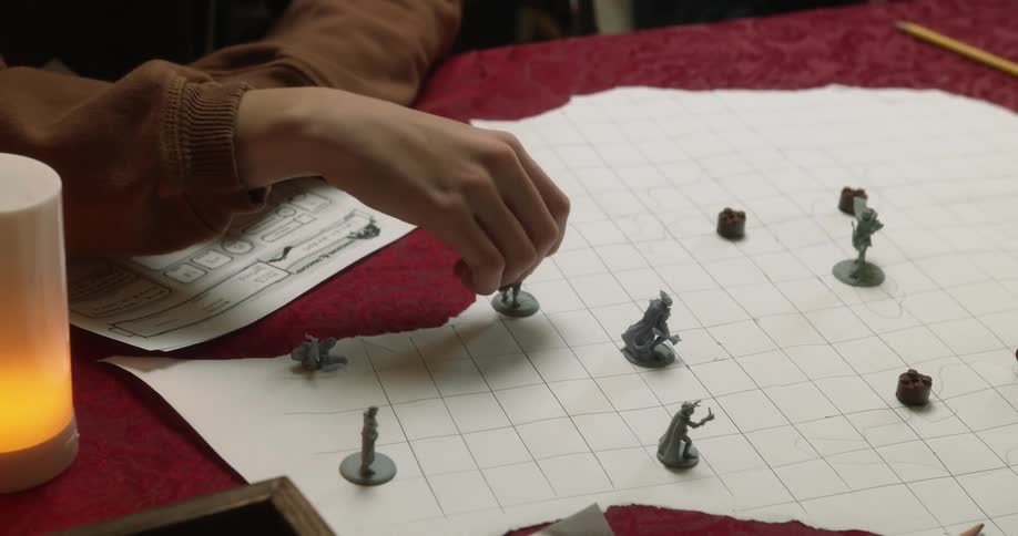 A person sitting at a table with a roleplaying game character sheet moves a miniature across grid on the tabletop