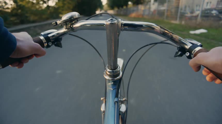 A bicyclist passes a man walking his down on a trail past a park POV