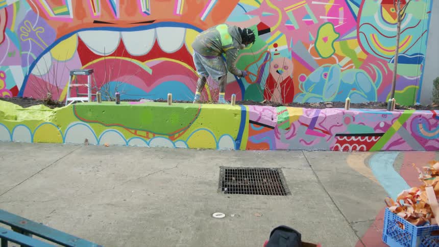 A man with a mask spray painting graffiti on a wall with a spray can