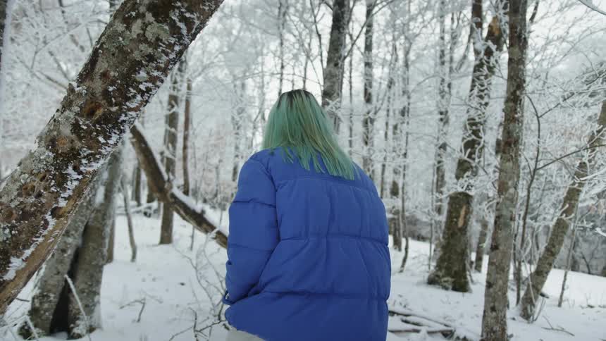 A woman walking through a snow covered forest