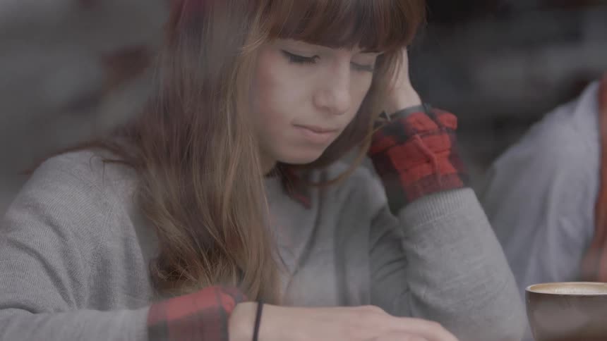 A young woman sits in a coffee shop reading a book