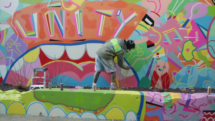 A man spray painting on a mural