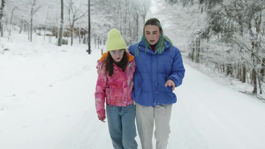 A woman walks with her arm around a girl through a snowy landscape talking and gesturing