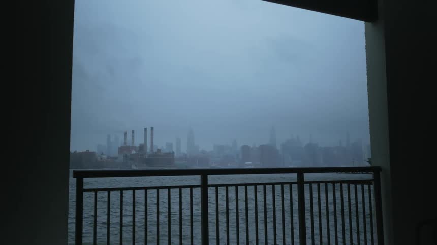 Fog blankets city buildings and factory visible over balcony rail